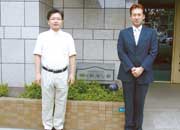 正面玄関前。前理事長の大村由紀夫氏（左）、現理事長の吉野秀徳氏（右）