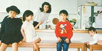 3歳ごろ、実家のダイニングにて。左から長兄・本人・母・次兄・妹