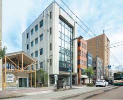 中央の白いビルがシェアハウス棟。左隣の2階建てがランドリー棟